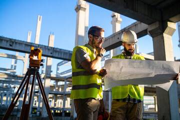 Ouvriers en gilets jaunes et casques de protection travaillant sur un chantier de construction avec équipement de mesure